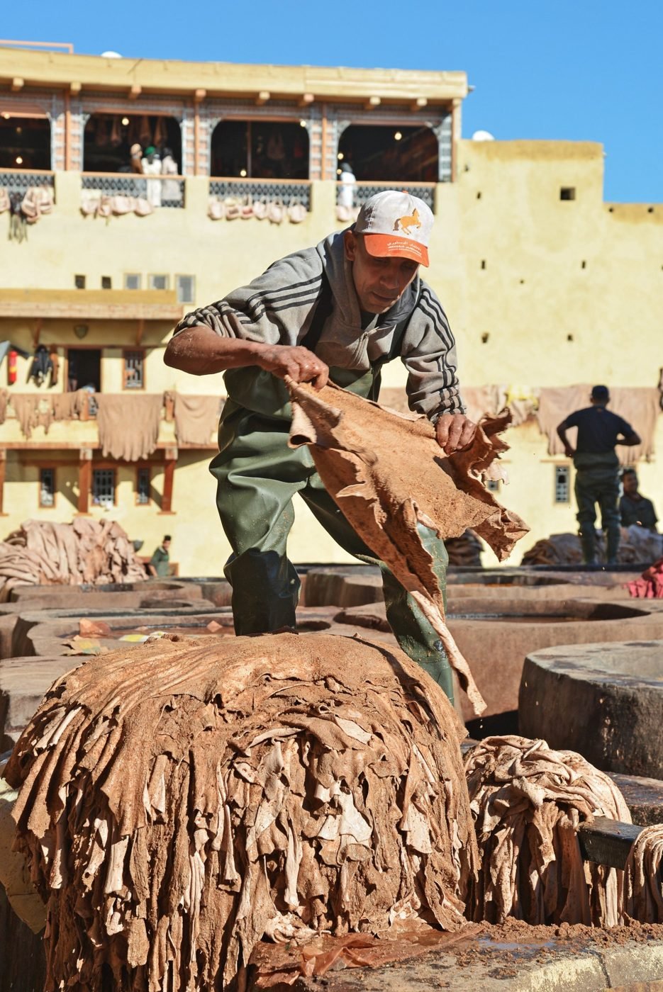 Artisan tanneur retournant des peaux au-dessus des cuves d'une tannerie traditionnelle à Fès